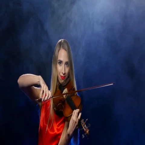 Woman in a red dress playing the fiddle. Studio. Smoke Stock Footage