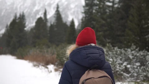 Woman in red hat walking through the snowy winter forest in High Tatra mountains Stock Footage 123080836