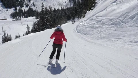 Woman in red jacket skiing down snowy mountain slope 库存影片 320398564