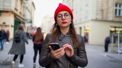 Woman with red lips using smartphone and strolls along the medieval street Stock Footage 74659459