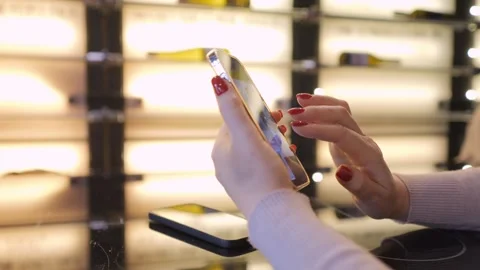 Woman with red nails using a smartphone in a modern cafe, interacting with the Stock Footage 277781318