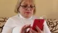 Woman with red smartphone sits on the sofa HD Footage