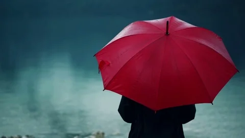 Woman with red umbrella contemplates on rain Stock Footage