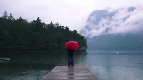 Woman with red umbrella contemplates on rain Stock Footage