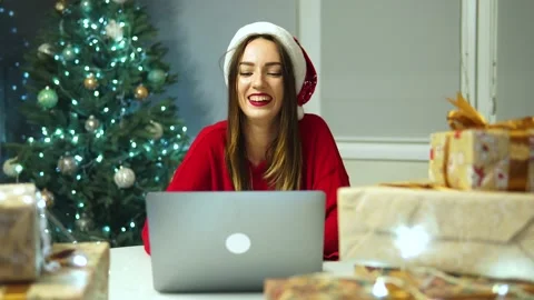 Woman in red xmas hat while working on laptop at home for Christmas and laughs Vidéo 164357740