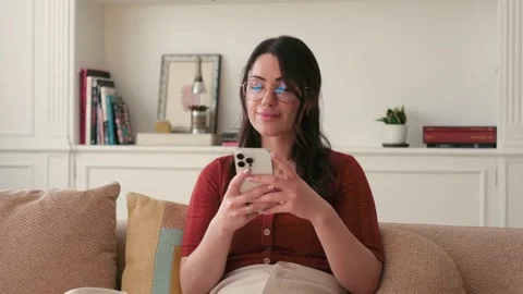 Woman Relaxing on Couch, Using Phone and Smiling Stock Footage 334014545