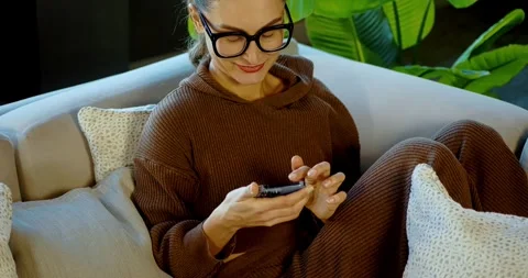 Woman Relaxing on Couch Using Smartphone in Cozy Living Room Stock Footage 324583466