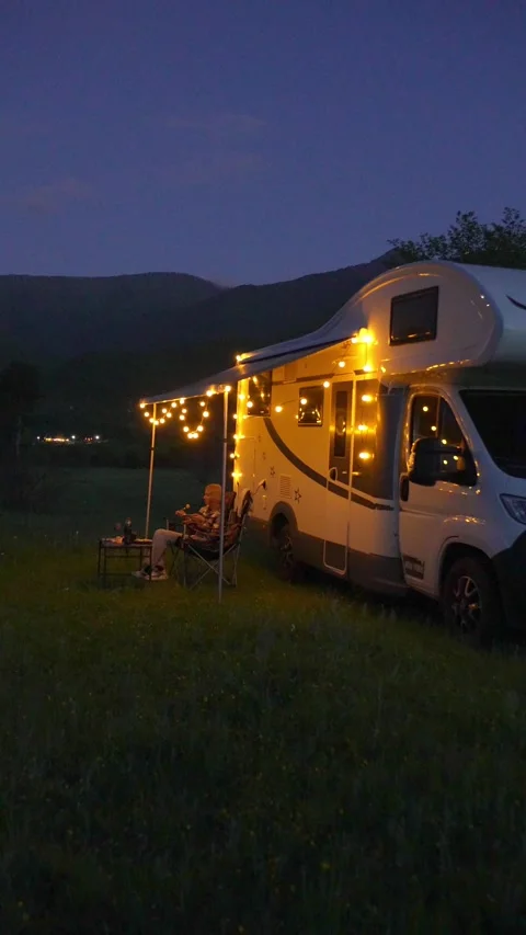Woman relaxing outside camper van during nighttime trip Stock-Footage 340261374