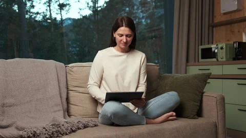 Woman relaxing on sofa using digital tablet in cozy living room Stock Footage 303497112
