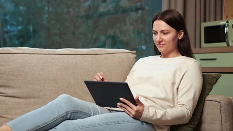 Woman relaxing on sofa using digital tablet Stock Footage 303498563