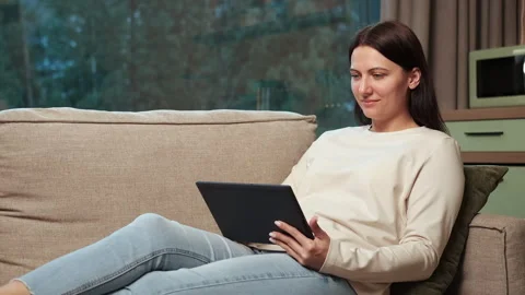 Woman relaxing on sofa using digital tablet Stock Footage 303499322