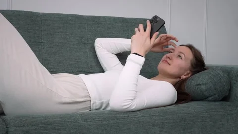Woman relaxing on sofa using smartphone 库存影片 308234538
