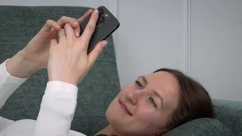 Woman relaxing on sofa using smartphone 스톡 동영상 308234570