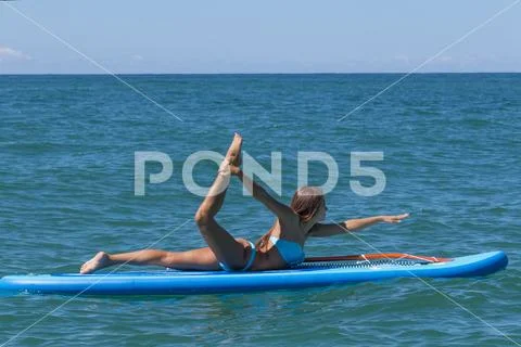 Woman relaxing on a SUP boarding in the sea. Paddle Board Yoga. Healthy Stock Photos