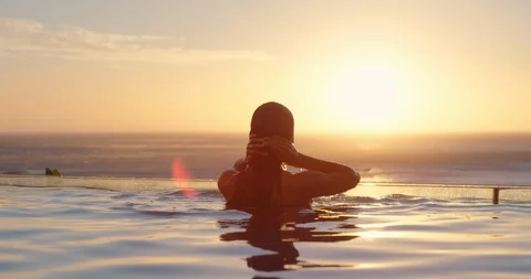 Woman relaxing in swimming pool at luxury hotel spa enjoying beautiful sunset Vidéo 111742375