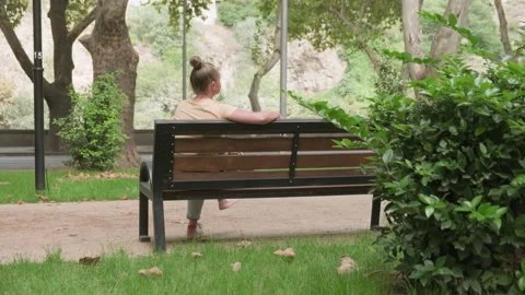 Woman relaxing while sitting on bench in city park Stock Footage 292307618