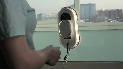 Woman remote control of cleaning robot. Window or mirror cleaning robot at home Stock Footage 170224366