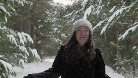Woman removing snow from tree while jumping in forest during winter Stock Footage 302556427
