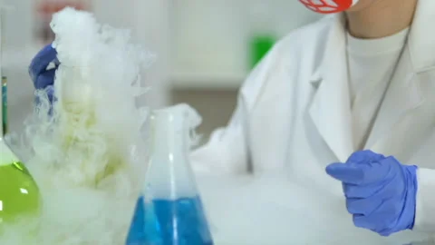 Woman from research lab examining sample of liquid during chemical reaction Stock Footage 104573993