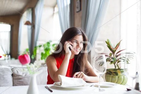 Woman in restaurant is talking to mobile phone Stock Photos