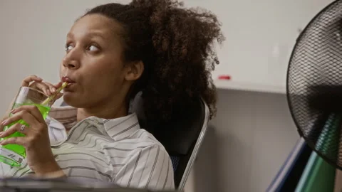 Woman Resting in Computer Chair while Fan Working Behind Her Stock Footage 335460394