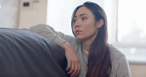 Woman resting head on couch back, lifting head, glancing right, stretching neck, Stock Footage 339496113
