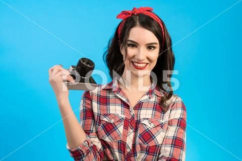 The woman with an retro camera standing on the blue background Stock Photos