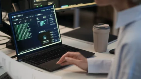 Woman Reviewing Document Working on Computers with Codes in Cybersecurity Office Stock Footage 334932886