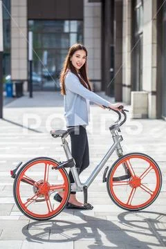 Woman riding a bicycle on city background Stock Photos