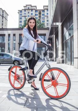 Woman riding a bicycle on city background Stock Photos