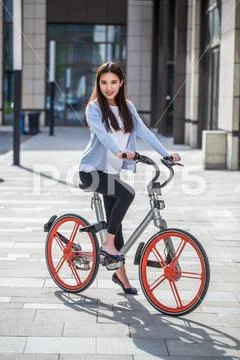 Woman riding a bicycle on city background Stock Photos