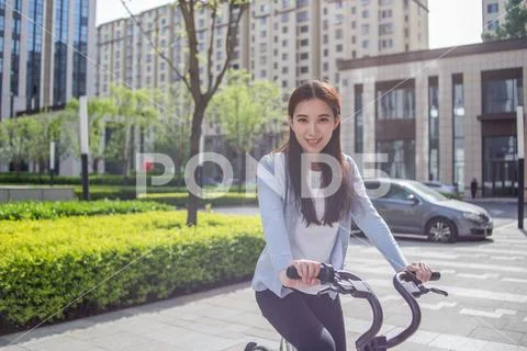 Woman riding a bicycle on city background Stock Photos