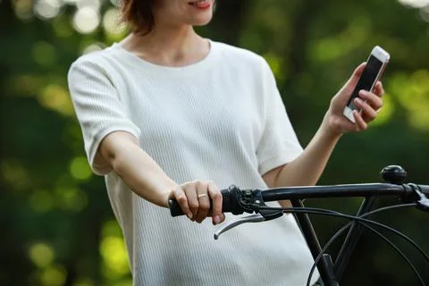 A woman riding a bicycle while using a smartphone Stock Photos