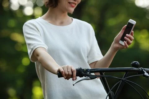 A woman riding a bicycle while using a smartphone Stock Photos
