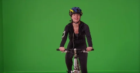 Woman riding her bicycle toward the camera with a helmet on green screen Stock Footage