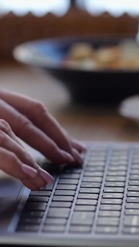 Woman with ring enters data using keyboard on portable computer at cafe table 스톡 동영상 346491079