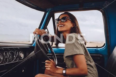 Woman on road trip driving a car and smiling Stock Photos