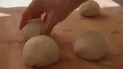 Woman rolling out flatbread dough on a wooden table Stock Footage 247376748