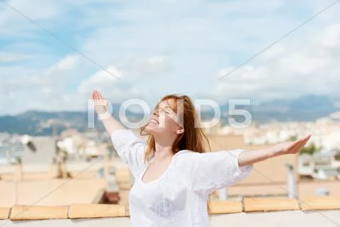 Woman on a rooftop embracing the sunshine Stock Photos