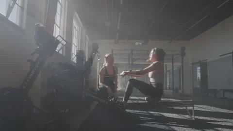 A Woman on a Rowing Machine While Her Trainer Watches Stock Footage 208800373