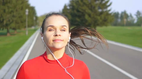Woman runner run on empty road. Red clothes, listen music in earphones. Slow Stock-Footage 107923146
