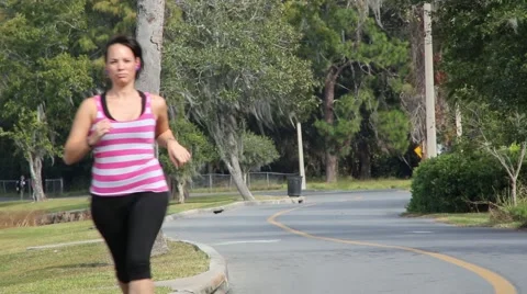 Woman running alongside road Stock Footage