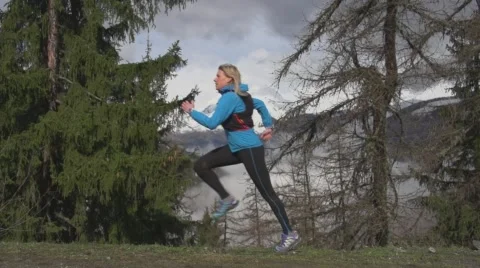 Woman Running Through Alpine Forest with Snow Capped Peaks in Distance. Vídeo Stock 59162241