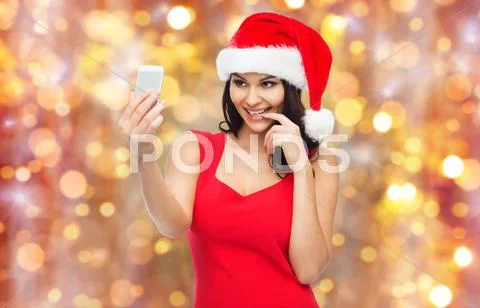 Woman in santa hat taking selfie by smartphone Stock Photos