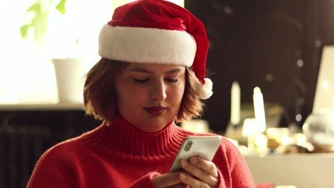 Woman in Santa hat using smartphone during Christmas holidays at home Stock Footage 339079016