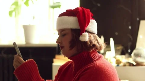 Woman in Santa hat using smartphone indoors during Christmas season Vidéo 339079018