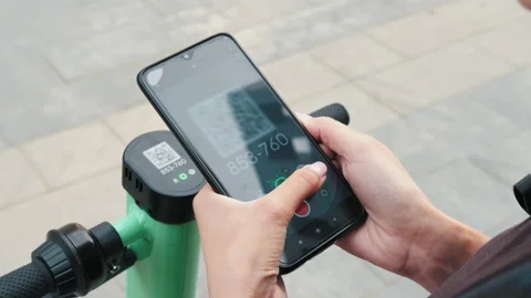 Woman scan QR code by smart phone to unlock and rent electric push scooter on Video stock 171986633
