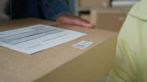 Woman Scanning Barcode on Package Held by Man in Warehouse 動画素材 337306501