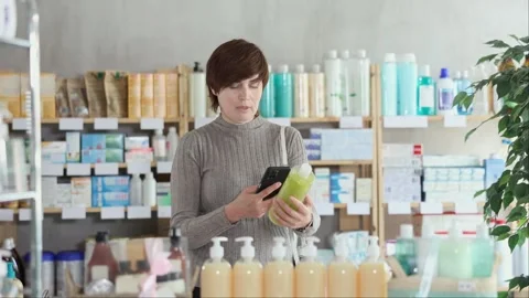 Woman scanning QR code on bottle on shower gel in store Stock Footage 329392679