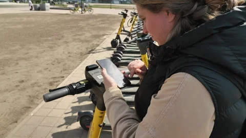 A woman scans the qr code on her electric scooter through a rental app Video stock 241215525